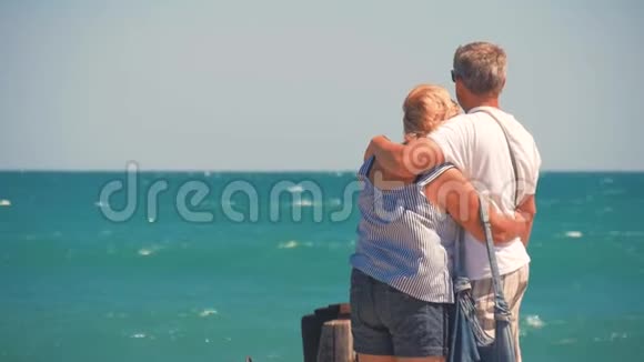 成熟的夫妻拥抱俯瞰大海一对漂亮的老人在水边快乐老人牵着手视频的预览图