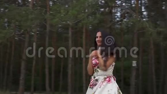 穿着长裙的漂亮女孩正在森林的背景下旋转视频的预览图