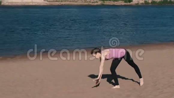 女人在城市河边的海滩上做瑜伽美丽的景色体操轮视频的预览图
