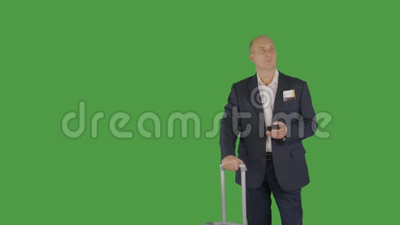 带旅行箱的商务人员带着绿色背景的手机视频的预览图