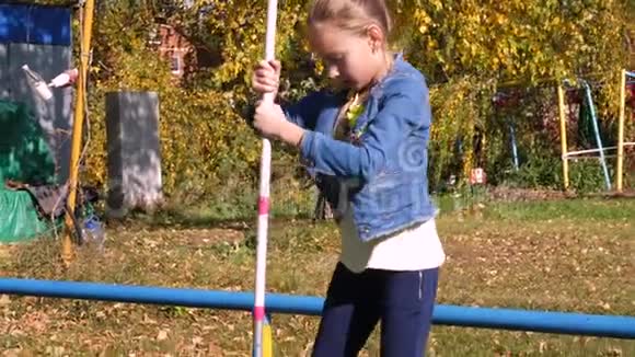 少年女孩在公园的障碍物中用杆在狭窄的横杆上行走视频的预览图