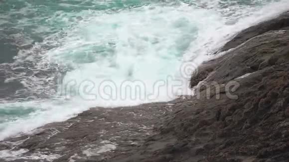 海沫落在岩石海岸上海洋中的绿松石波视频的预览图