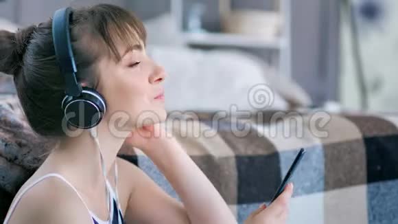 女性音乐爱好者使用智能手机在耳机中收听和欣赏喜爱的音乐视频的预览图