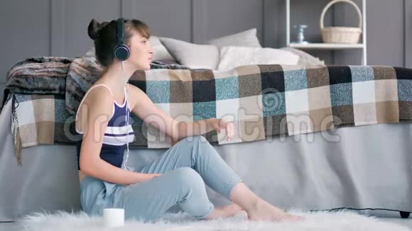 侧视图年轻休闲少女跳舞享受声音听着耳机里最喜欢的音乐视频的预览图