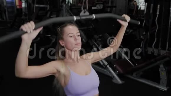 有着美丽身材的运动女性在健身房训练她回到模拟器上视频的预览图