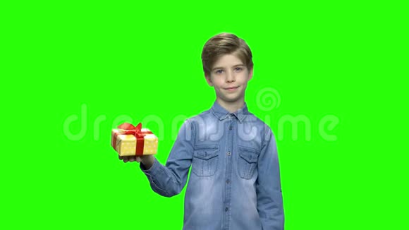 可爱的小男孩用红色丝带指着黄色的礼盒视频的预览图