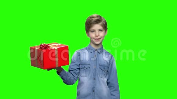 穿牛仔夹克的男孩拿着红色的礼盒和手指视频的预览图