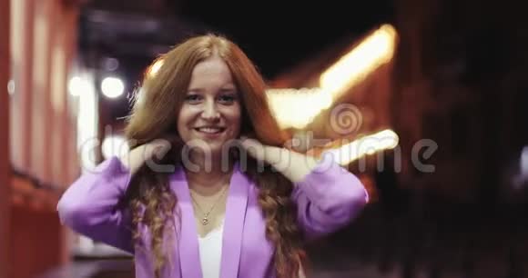 一个有着红色卷发的快乐女孩正在夜城散步视频的预览图