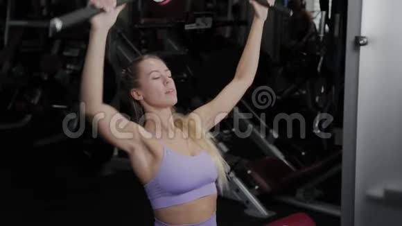 有着美丽身材的运动女性在健身房训练她回到模拟器上视频的预览图