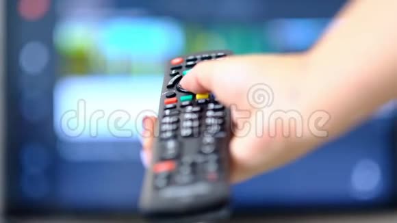 慢动作的女人看电视按下遥控器上的按钮手拿着电视遥控器关掉视频的预览图