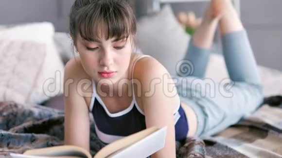 中镜头聚焦年轻女性阅读书籍躺在床上躺在家里视频的预览图