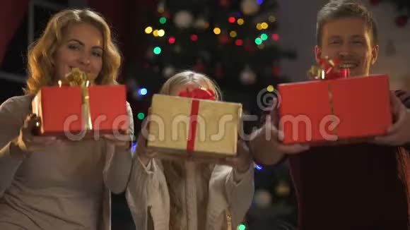微笑的父母和女儿向镜头展示礼物圣诞愿望清单视频的预览图