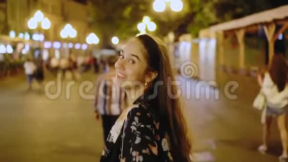 美丽的女孩沿街走着夜城特写镜头微笑着视频的预览图