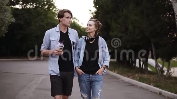 傍晚时分穿着黑色T恤和蓝色衬衫的漂亮年轻朋友正在公园散步聊天约会视频的预览图