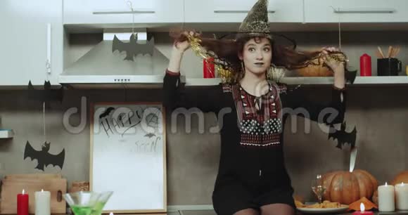 万圣节前夜在厨房里滑稽的女巫在镜头前扮演着魅力四射的角色她有一张亚洲脸视频的预览图