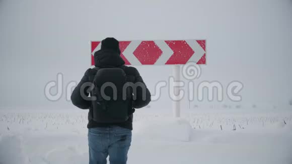 徒步旅行者带着背包在道路上的冬天选择在两个不同的道路方向之间的道路岔路口概念视频的预览图
