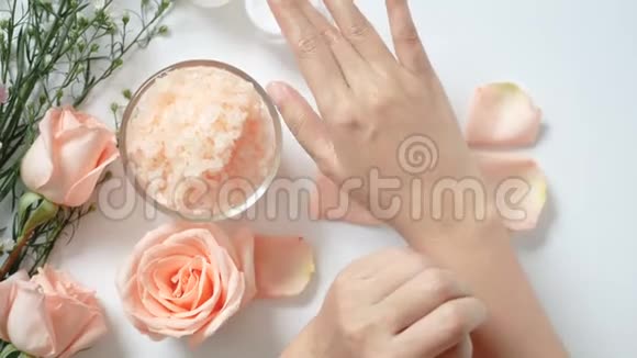 4K自然护肤概念女人把白色奶油涂在她的手上白色背景上有一罐霜盐水疗擦洗视频的预览图