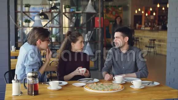 漂亮的年轻女孩正在比萨饼店和她的朋友见面做高五和朋友聊天喝茶友谊视频的预览图