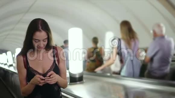 在地铁或地铁的自动扶梯上美丽的女人在电话中微笑视频的预览图