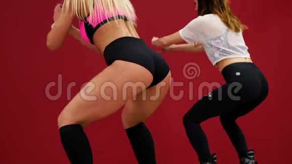 红墙背景上的一个漂亮的女孩做蹲以加强大腿肌肉臀肌训练视频的预览图