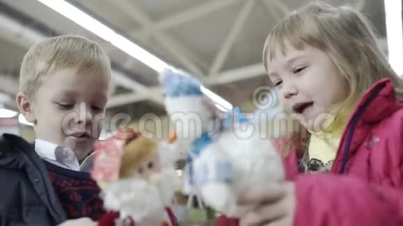 可爱的女孩和男孩在购物中心玩圣诞玩具慢动作视频的预览图