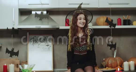 年轻女子戴着女巫面具站在厨房的桌子上对着镜头演奏表情非常鲜明视频的预览图