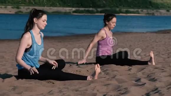 两个女人在城市河边的海滩上做瑜伽城市美景个人培训视频的预览图