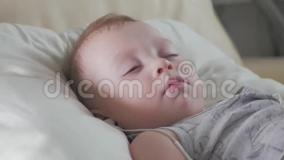 可爱的婴儿带着耳机甜蜜地睡在家里的床上视频的预览图