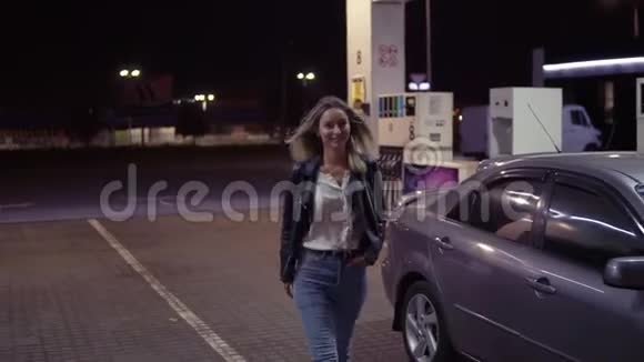 卡瓦尔加油站的浪漫微笑的女人肖像背景中的汽车行走和摆姿势正面观点视频的预览图