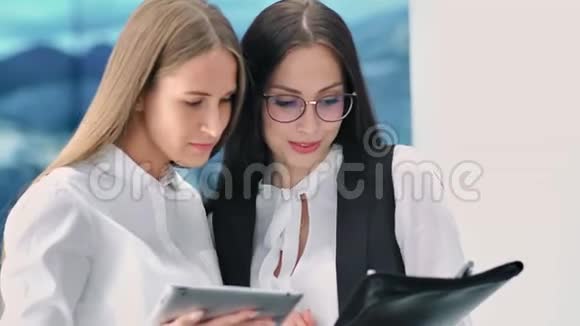 两位女商人正在讨论使用平板电脑进行现代实验室的新项目视频的预览图