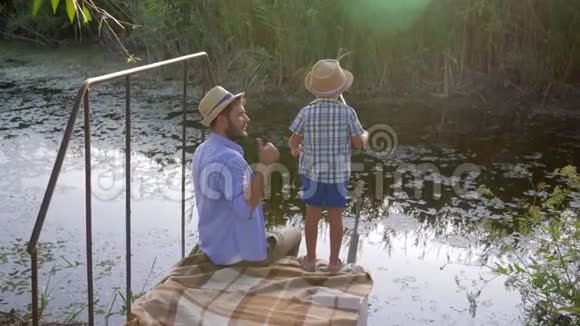 钓鱼爸爸在小河边的家庭娱乐活动中教儿子钓鱼视频的预览图