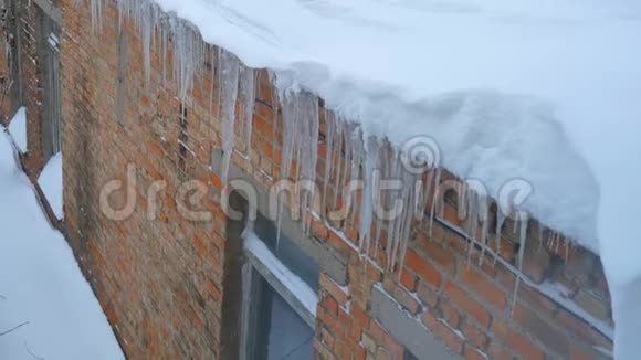 很多冰柱挂在砖墙背景的屋顶上视频的预览图