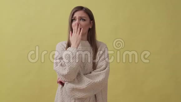 年轻失望的女孩站在黄色背景下看着摄像机视频的预览图