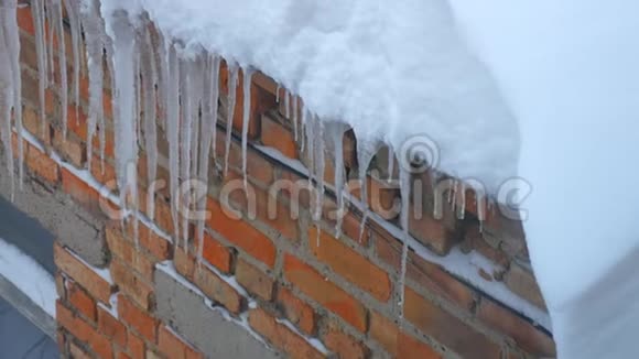 很多冰柱挂在砖墙背景的屋顶上视频的预览图