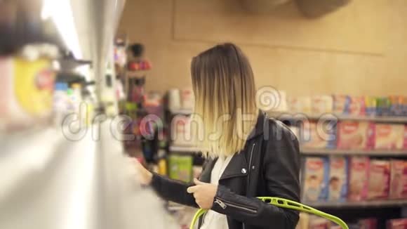 女人在超市里选择酸奶金发微笑的女人在购物中心选择产品女孩站在附近视频的预览图