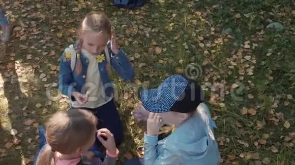 三个少女在城市公园休息时吃糖果视角很高视频的预览图