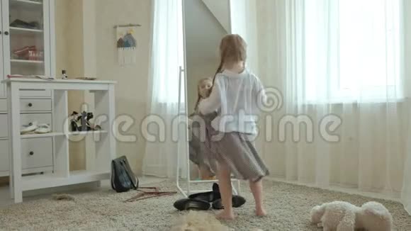 穿着粉红色裙子扎着辫子的开朗女孩试着穿着成年妈妈衣服连衣裙高跟鞋和在前面跳舞视频的预览图