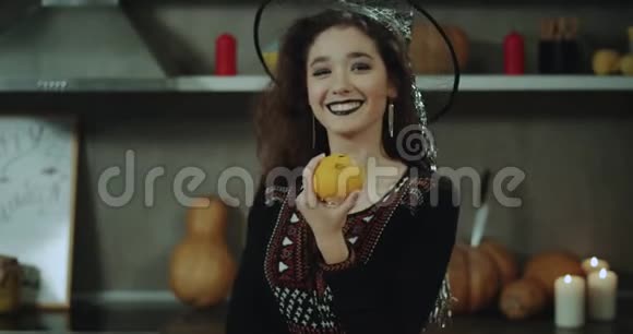 万圣节派对上一个戴着面具的可爱女巫在镜头前玩一个装饰好的橙色非常有魅力的女士视频的预览图