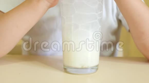 一个孩子通过吸管从杯子里喝牛奶把气泡吹成玻璃杯一杯牛奶特写视频的预览图