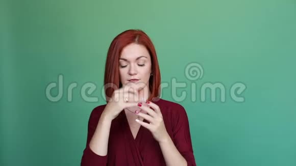 红头发的女人在绿色背景的工作室摆姿势从手指上掏出戒指视频的预览图