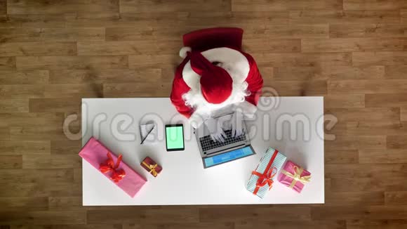 圣诞老人在办公室工作手提电脑平板电脑带有色度绿色屏幕打字鸟瞰自上而下的拍摄视频的预览图