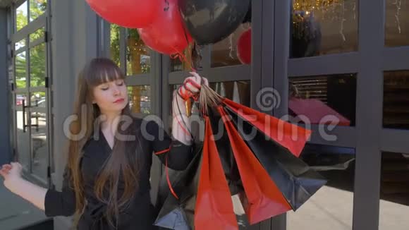 折扣季节购物狂的女孩在购物后拿着袋子用气球在购物时展示手指然后在购物时展示视频的预览图