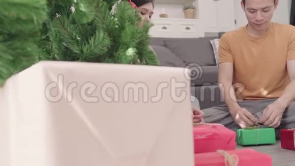 亚洲夫妇包装圣诞礼物装饰他们的客厅在圣诞节在家视频的预览图
