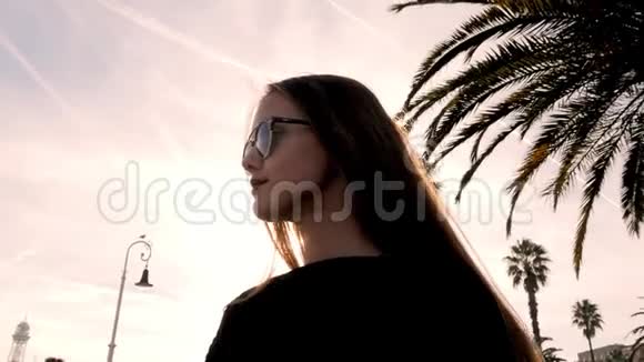 时尚少年戴着太阳镜站在海滩上手捧棕榈树戴墨镜的金发模特视频的预览图
