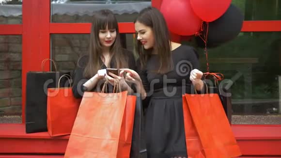 网上购物快乐的年轻女性手里拿着纸袋红色背景下用智能手机在线购物视频的预览图
