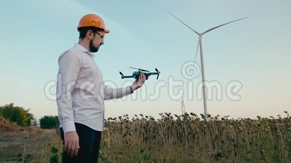 戴着橙色防护头盔和护目镜的白种人工程师用手发射了一架智能四翼无人机视频的预览图