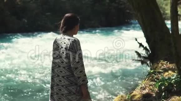 迷人的年轻女子走在森林的河岸边坐在那里视频的预览图