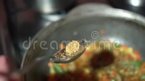 厨师用冷冻蔬菜混合物在锅中加入辛辣的香料视频的预览图
