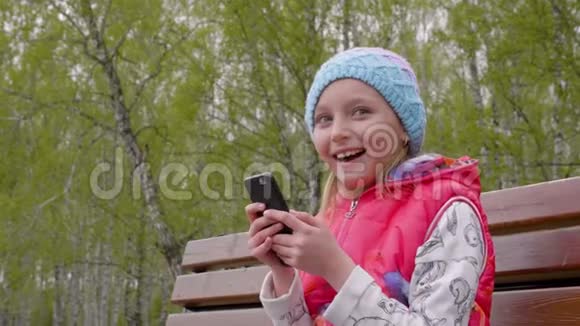 在公园的长椅上聊天和打电话的年轻女孩视频的预览图