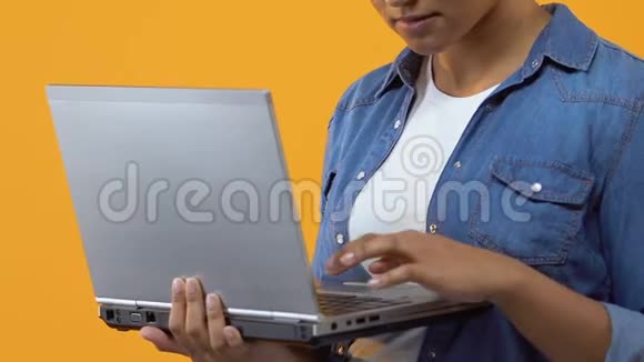 女性自由职业者在黄色背景下输入笔记本电脑键盘视频的预览图